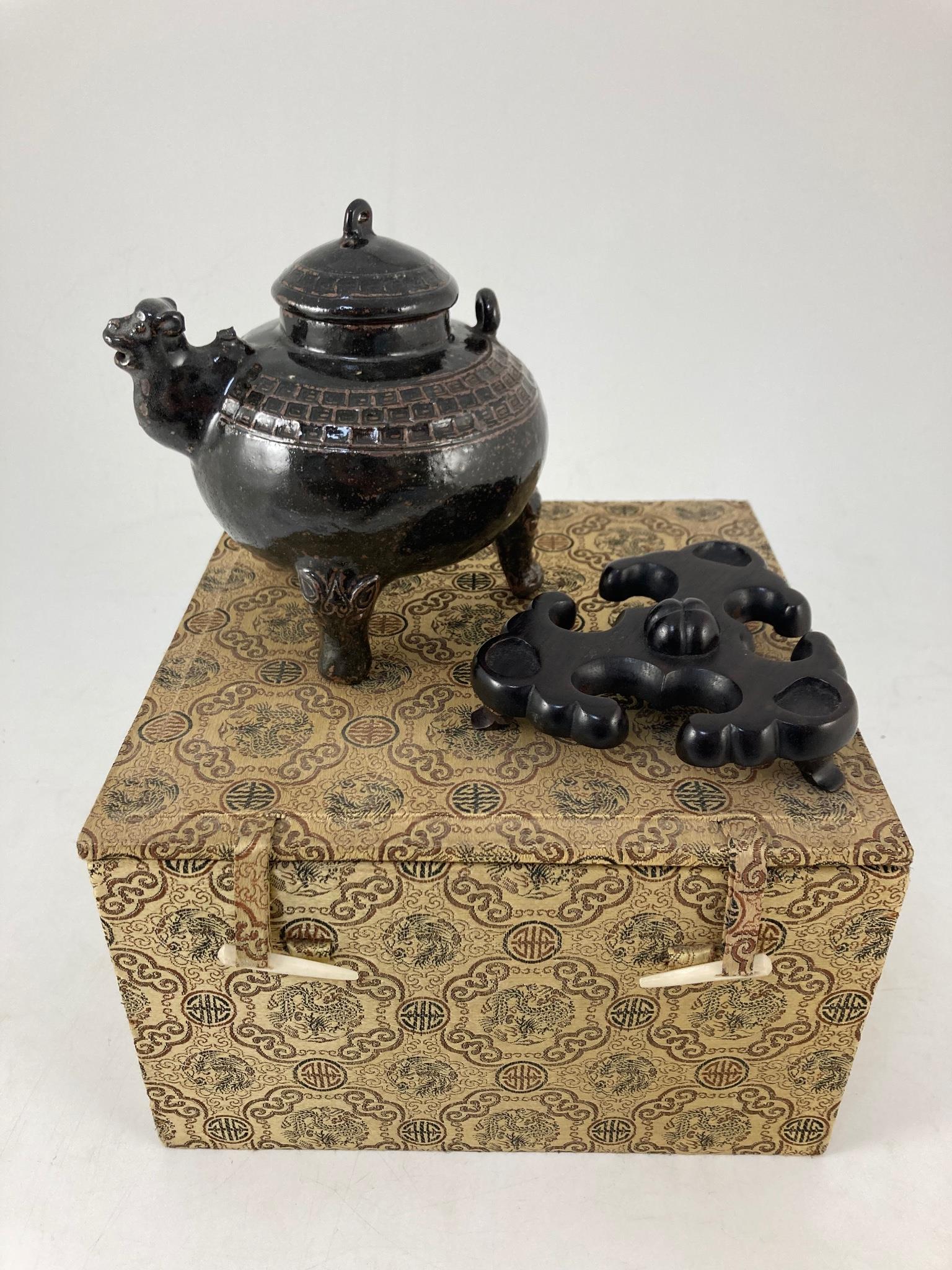 An unusual Chinese black ware tenmoku glazed tripod wine pot, 19th/20th century, with camel head spout, zoomorphic feet, 14cm high, hongmu stand